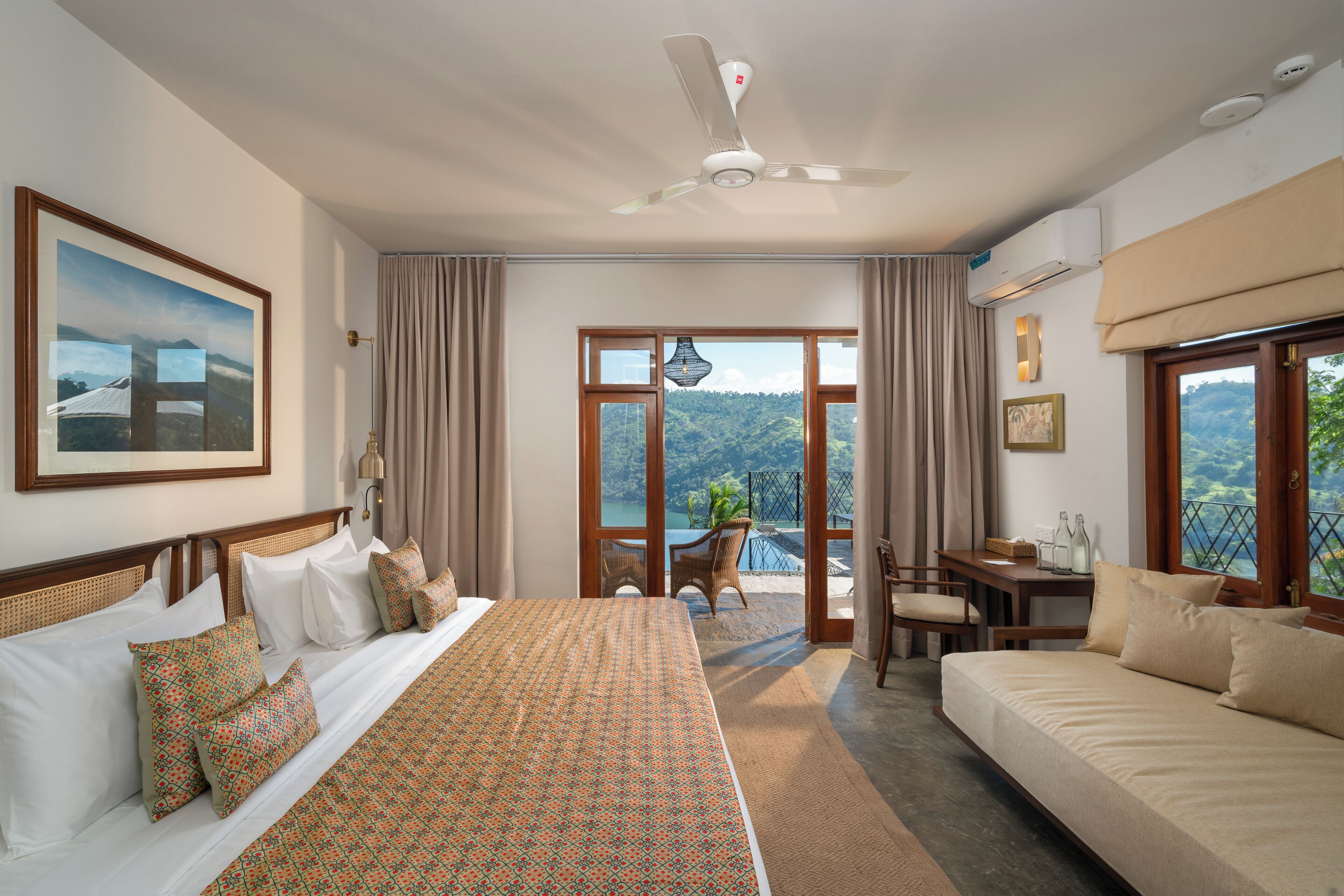 Habitación de hotel con una cama grande, un sofá, un escritorio y vistas al exterior.