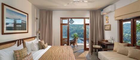Habitación de hotel con una cama grande, un sofá, un escritorio y vistas al exterior.