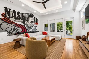 A modern living room with a large wall mural, a sofa set, a coffee table, and a ceiling fan.