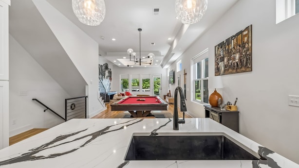 A modern interior with a pool table, pendant lighting, and a large painting on the wall. - Luxury home with rooftop lounge near Broadway! (Nashville)