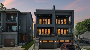 A modern multi-story residential building with a garage, a staircase, and a red pickup truck parked in front. - Luxury home with rooftop lounge near Broadway! (Nashville)