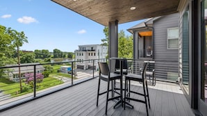 A balcony with a table and chairs, overlooking a lake and residential buildings. - Luxury home with rooftop lounge near Broadway! (Nashville)
