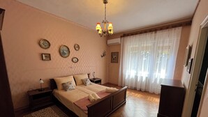 Un dormitorio con una cama grande, una mesita de noche, una lámpara, un tocador y una araña.