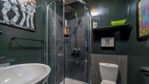 A bathroom with a glass-enclosed shower, a white sink, and a toilet. - Charming Studio moments from Portobello (London)