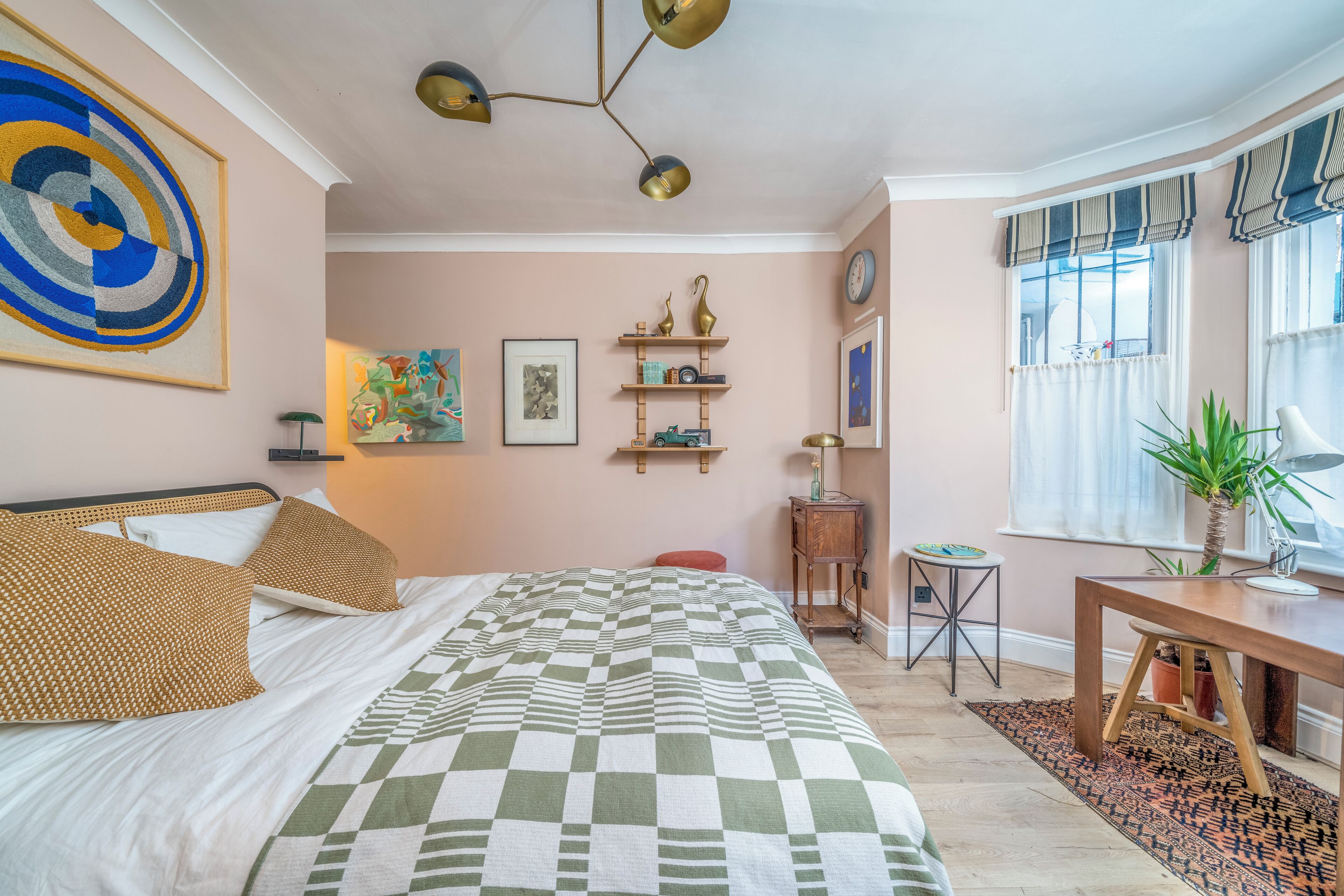 Une chambre à coucher avec un grand lit, une table de chevet, une petite table et une fenêtre avec des rideaux.