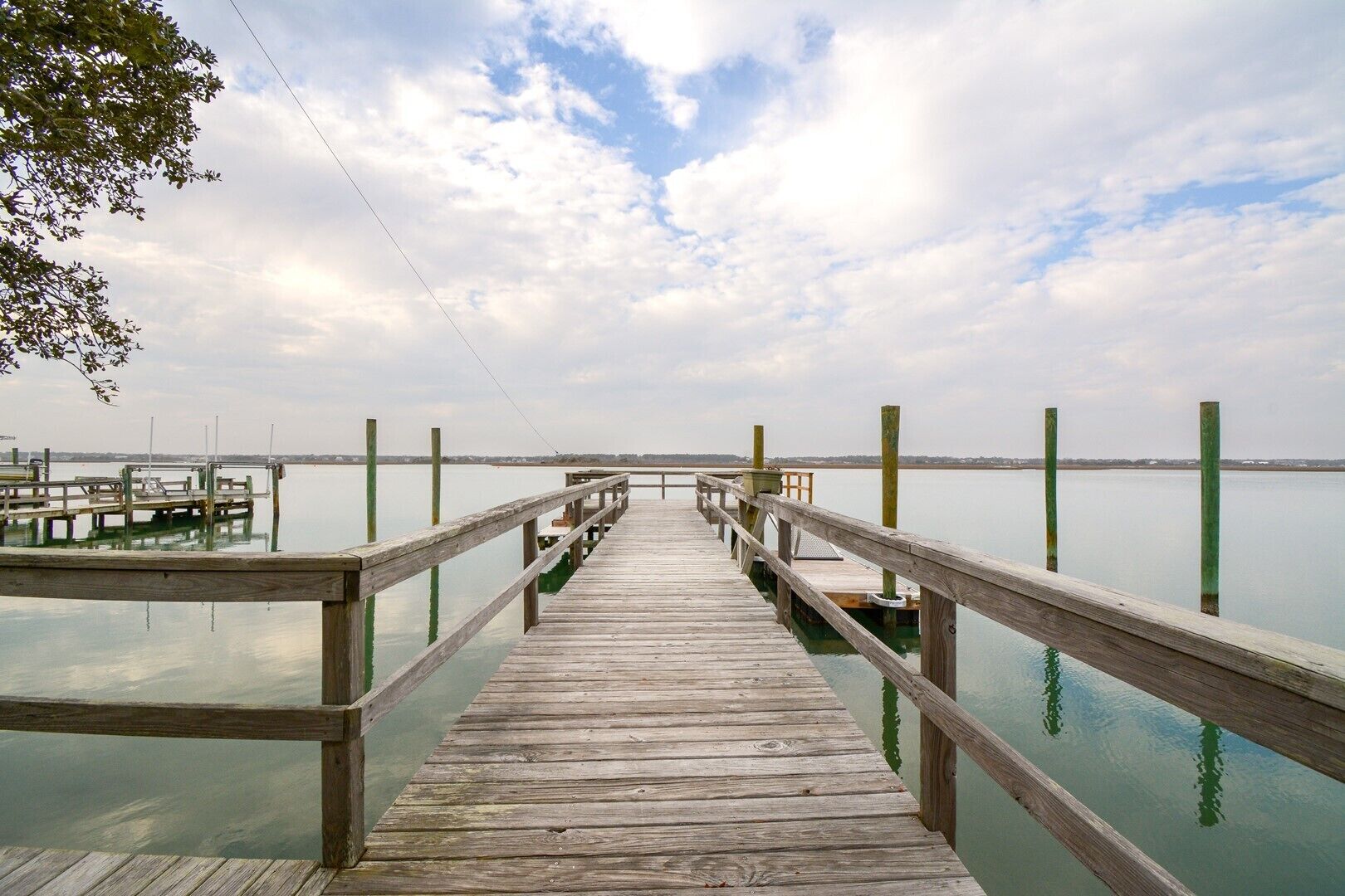 A wooden pier extending into calm water with a clear sky above.