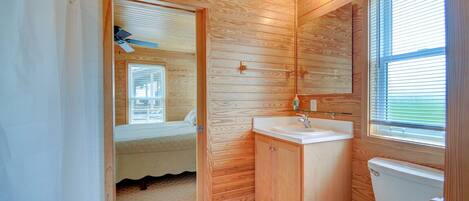 A compact wooden bathroom with a toilet, sink, and mirror.
