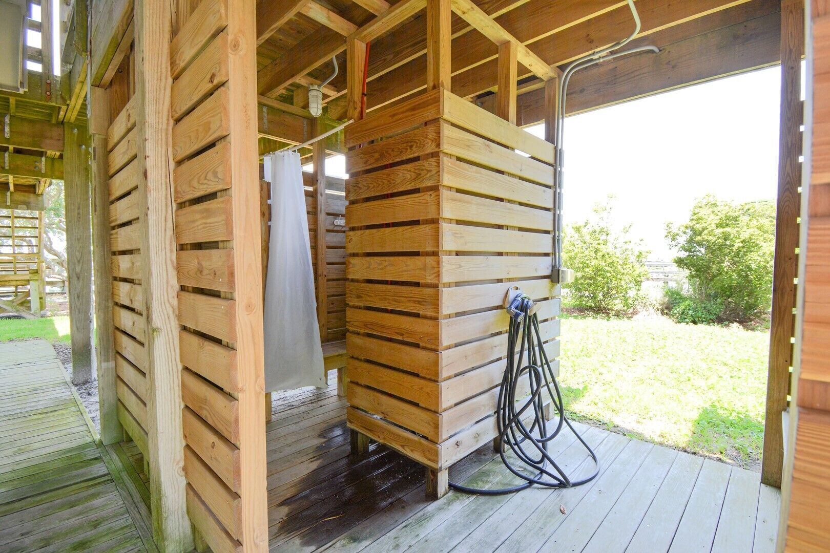 Eine Holzhütte mit überdachter Terrasse, inklusive Holzdeck und einem überdachten Bereich mit Pendelleuchte.