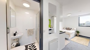 Casa de banho moderna com sanita, lavatório, espelho e chuveiro.