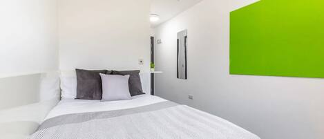 Een moderne hotelkamer met een bed, een groene accentmuur en een minimalistisch design.