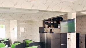 A lobby with green and black seating, a reception desk, and a marble-patterned wall. - Ted G Hotel (Port Harcourt)