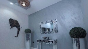 A modern bathroom with a grey wall, a decorative mirror, a sink with a geometric design, and two tall vases with spherical tops. - Ted G Hotel (Port Harcourt)