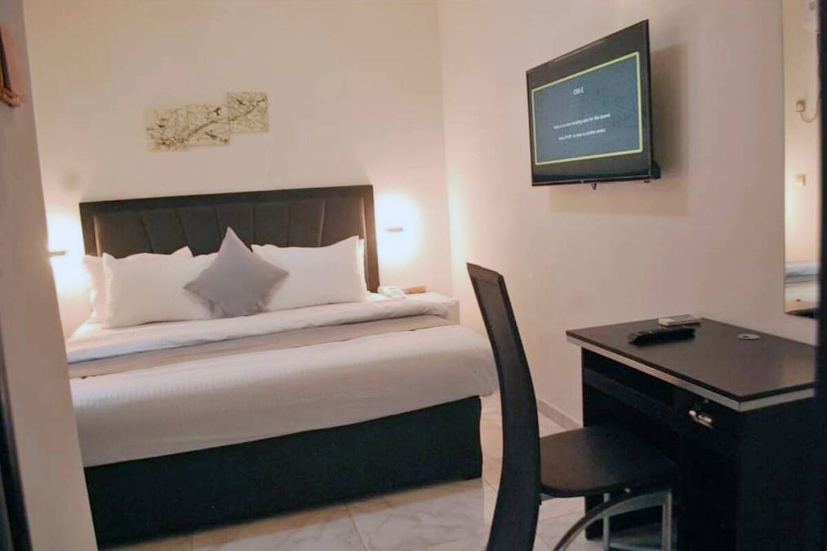 A hotel room with a bed, a desk, and a television mounted on the wall.