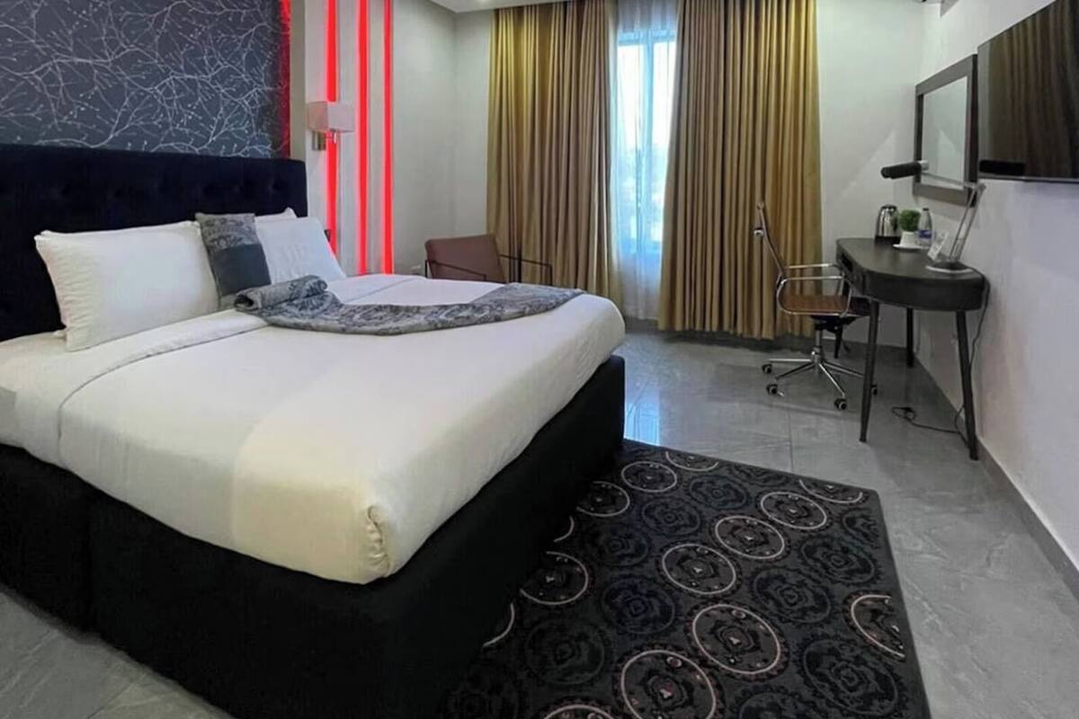 A modern hotel room with a large bed, a desk, and a chair.