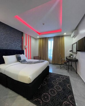 Een moderne hotelkamer met een groot bed, een bureau en een stoel.