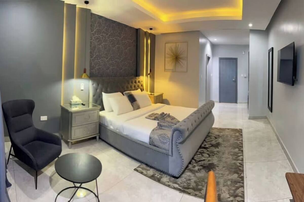 A modern bedroom with a large bed, a nightstand, a chair, and a small table.
