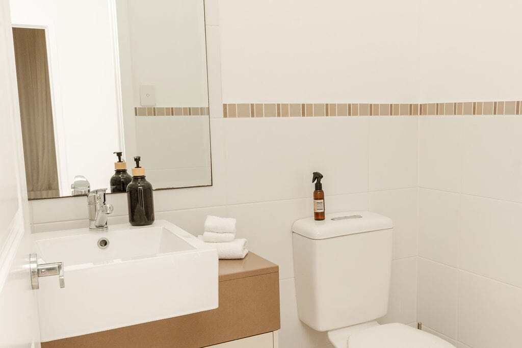 A bathroom with a white sink, a mirror, a toilet, and a towel rack.