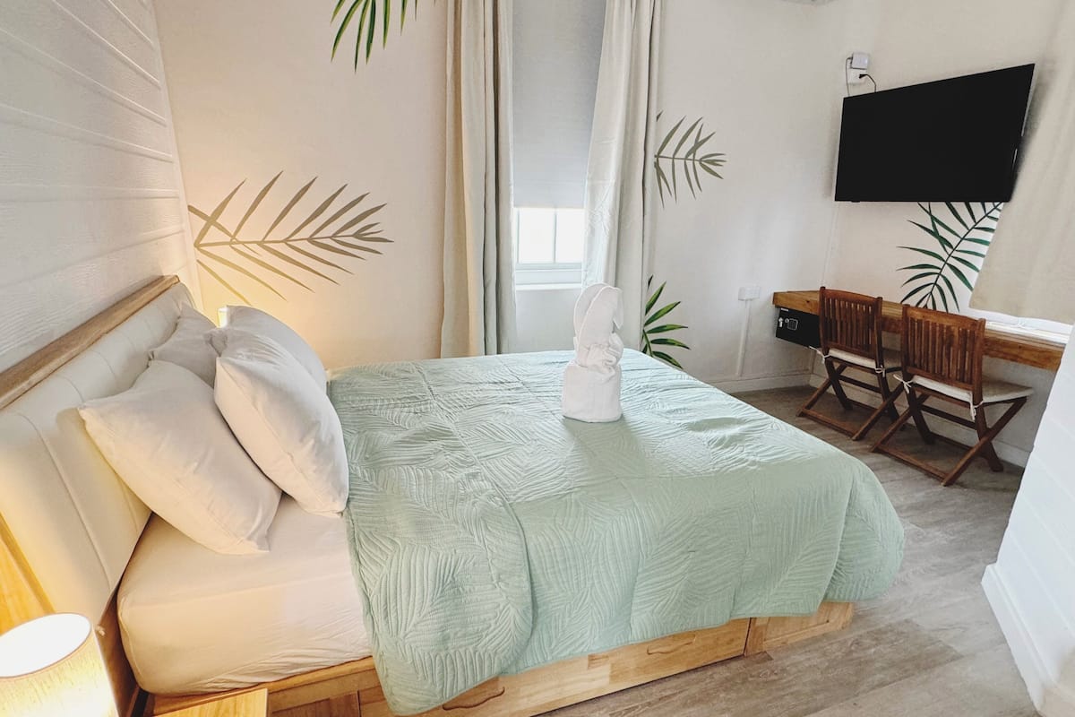 A bedroom with a bed, a desk, a chair, and a TV.