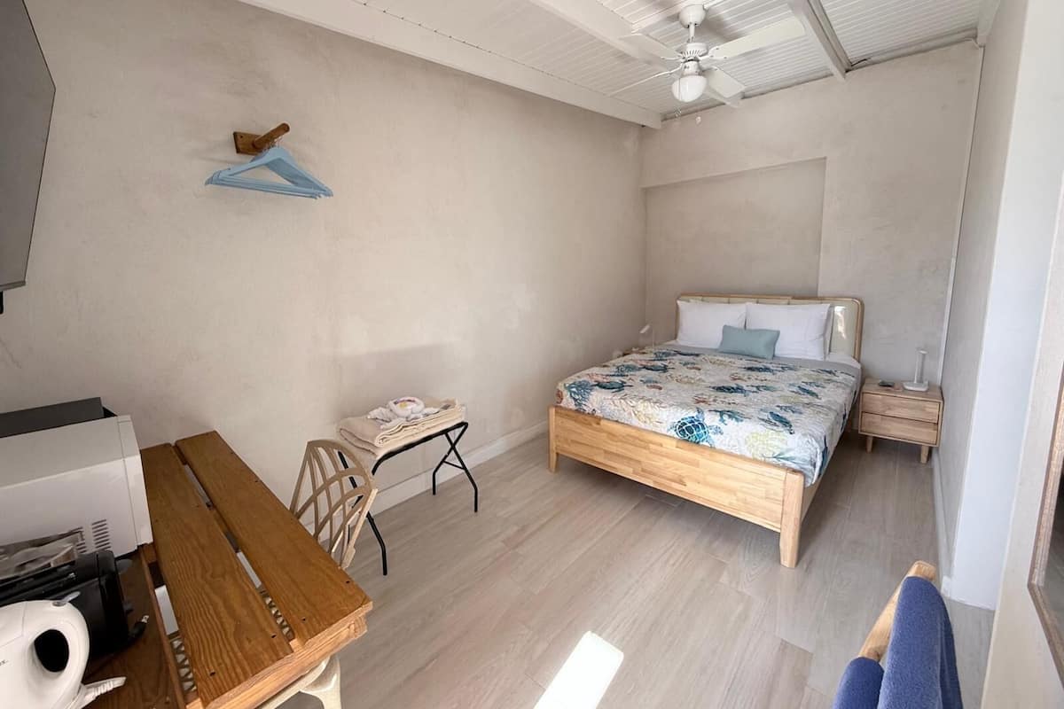 A bedroom with a bed, a desk, a chair, and a ceiling fan.