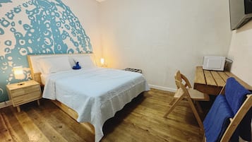 A bedroom with a bed, bedside tables, a chair, a desk, and a TV.
