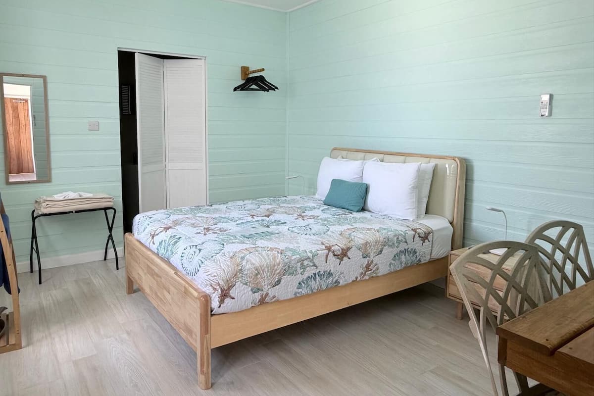 A bedroom with a bed, a desk, and a chair.