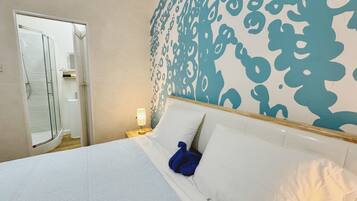 A hotel room with a bed, a shower, and a wall with a blue abstract pattern.