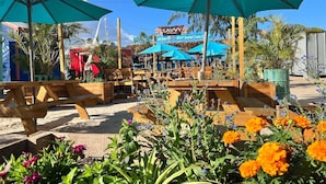 Een restaurant aan het strand met terras en grote parasols.