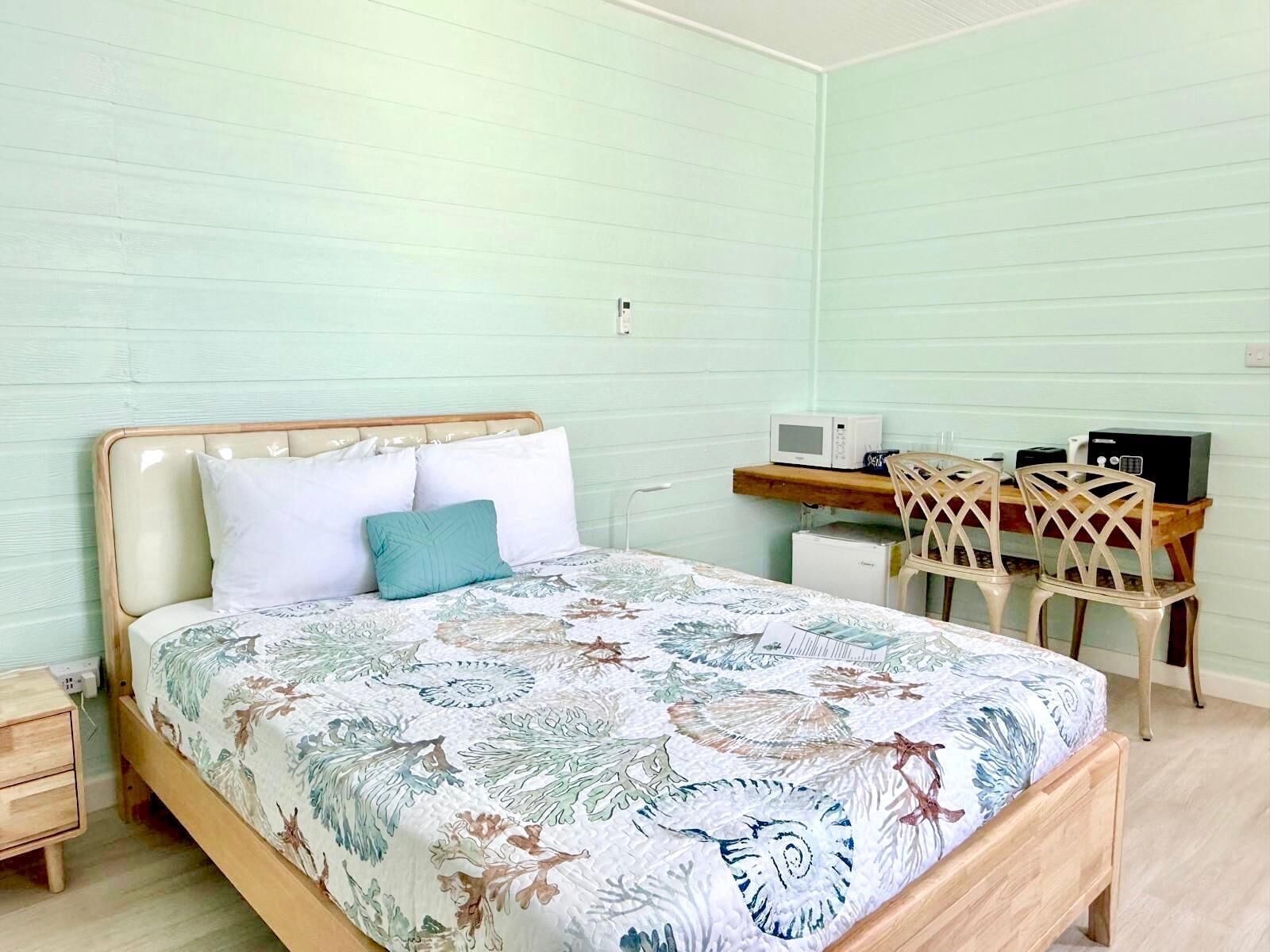 A bedroom with a bed, a desk with a computer, and a chair.