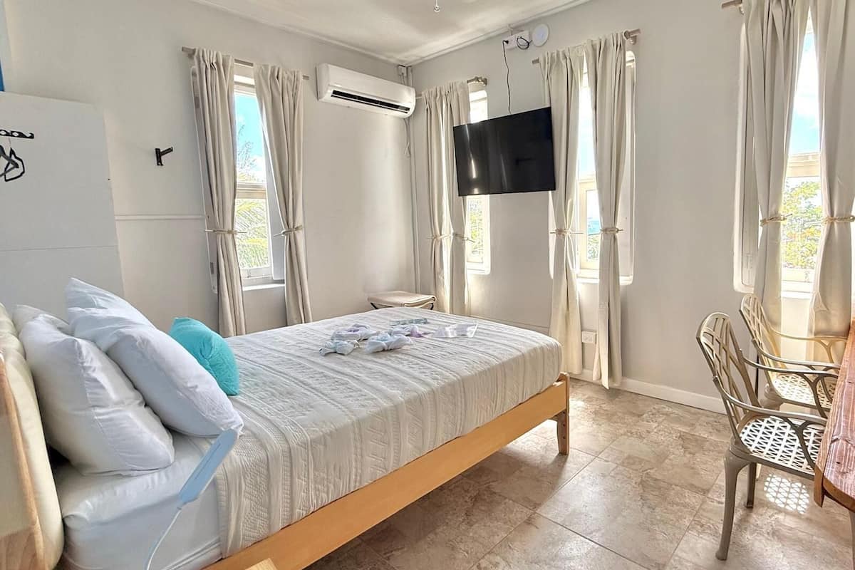 A bedroom with a bed, a TV, a desk, and curtains.