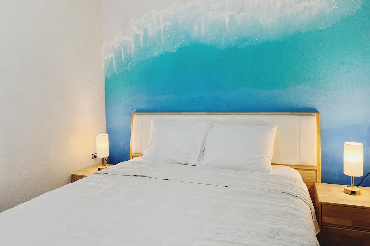 A bed with white bedding, a wooden headboard, and two bedside lamps.