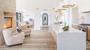 A spacious living area with a fireplace, comfortable seating, a kitchen with a marble island, and a dining area with natural light. - Ultra-Luxe Escape | Sleeps 16 | Minutes to RT (Carmine)