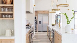A modern kitchen with wooden cabinets, a central island, and pendant lighting. - Ultra-Luxe Escape | Sleeps 16 | Minutes to RT (Carmine)