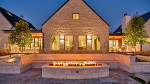 A stone building with a fire feature in the center, surrounded by seating areas and trees. - Ultra-Luxe Escape | Sleeps 16 | Minutes to RT (Carmine)