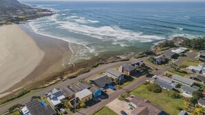 Vista aérea de una zona residencial costera con casas, una playa y el océano.