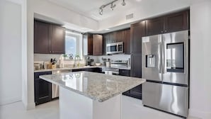 Una cocina moderna con armarios oscuros, electrodomésticos de acero inoxidable y una isla central.