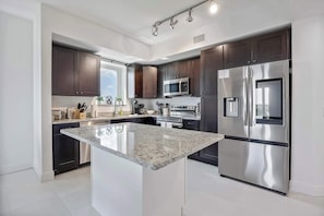 A modern kitchen with dark cabinets, stainless steel appliances, and a central island.