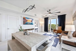 A modern hotel room with a dining area, a sofa, a lamp, and a ceiling fan.
