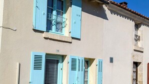 Un bâtiment à deux étages avec des murs de couleur claire et des volets bleus.