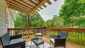 A covered outdoor deck with wicker furniture and a glass table. - Pet-Friendly Lake Norman Retreat (Mooresville)
