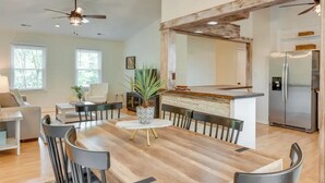 A spacious living room with a wooden dining table, modern chairs, and a kitchen area with a stainless steel refrigerator. - Pet-Friendly Lake Norman Retreat (Mooresville)