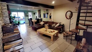 A modern living room with a wooden coffee table, a brown sofa, and a staircase. - Private room at the foot of the Cevennes (Lodève)