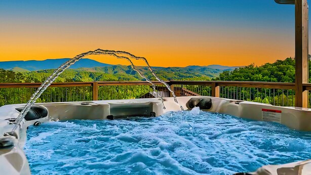 A hot tub with a view of mountains and greenery. - Casa Bella: Mtn Views, Movie Room, Games, Hot Tub, Wifi, Yard with Fire Pit! (Sevierville)