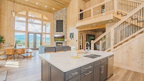 A spacious kitchen with a large island, wooden floors, and a view of the outdoors. - Casa Bella: Mtn Views, Movie Room, Games, Hot Tub, Wifi, Yard with Fire Pit! (Sevierville)
