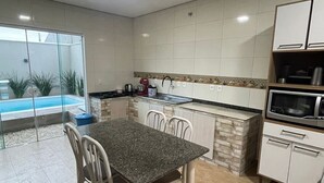 Cocina moderna con comedor, horno empotrado y vista a una piscina.