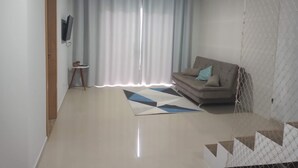 Una sala de estar moderna con un sofá, una mesita y un televisor montado en la pared.