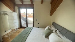 A bedroom with a bed, a wardrobe, a bench, and a view through a sliding door. - Orchidea Apartment (Seregno)