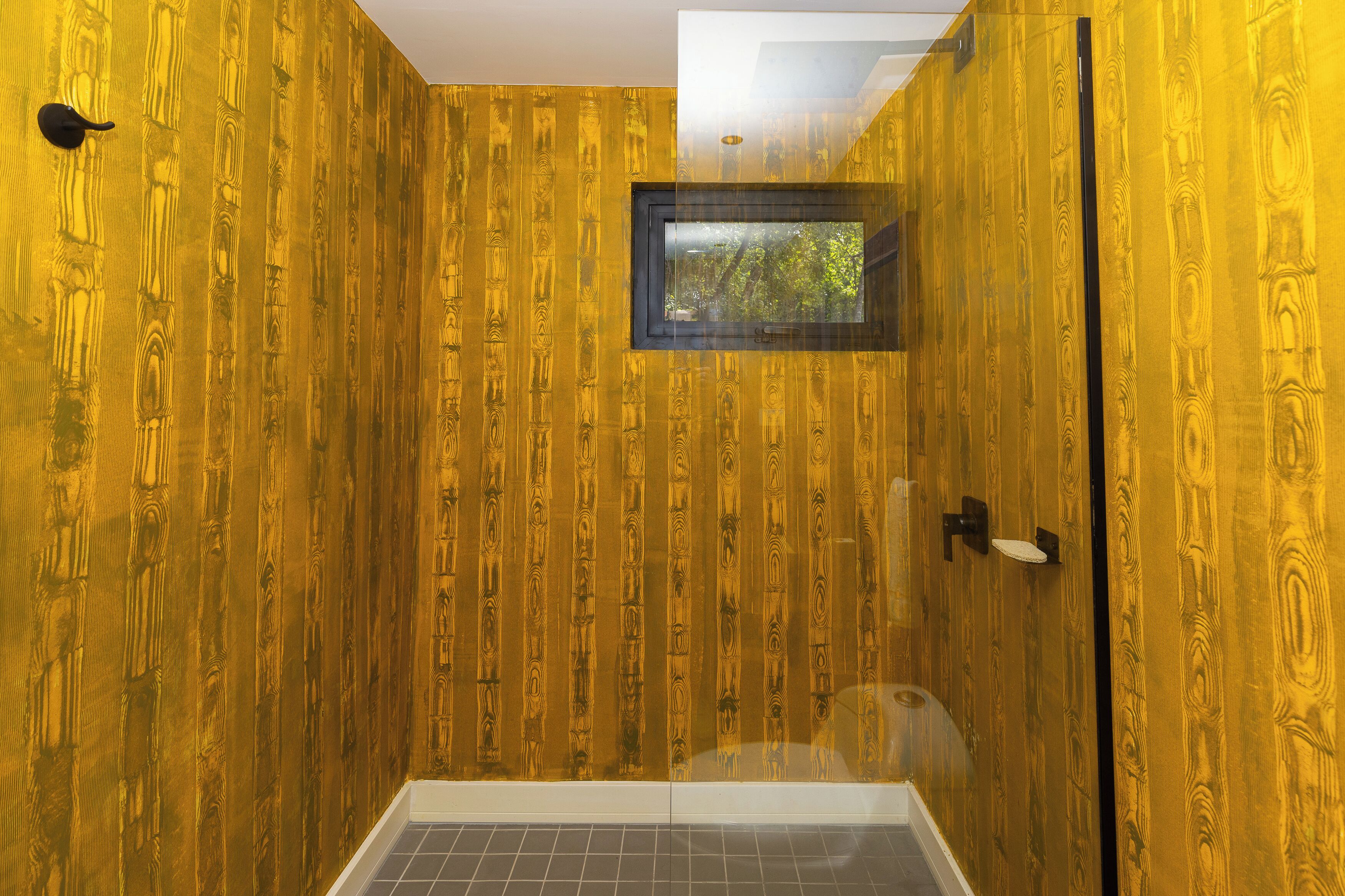 Une salle de bain avec un lambris en bois vertical et une petite fenêtre.