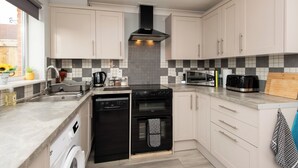 A modern kitchen with white cabinets, a black stove, and a microwave. - Darlington 3 bed House Near Train Station (Darlington)