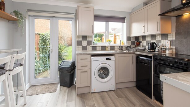 A compact kitchen with a washing machine, dishwasher, and oven. - Darlington 3 bed House Near Train Station (Darlington)