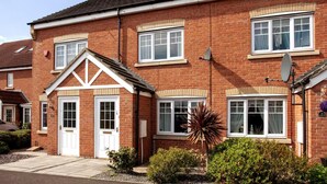A two-story brick house with white-framed windows, a front door, and satellite dishes. - Darlington 3 bed House Near Train Station (Darlington)